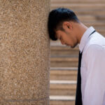 business man crying abandoned lost in depression sitting on ground street concrete stairs suffering emotional pain